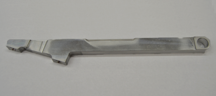 Long machined aluminium bracket with a stepped profile and bored end